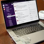 A laptop displaying a communication app next to eyeglasses and a coffee cup on a table.
